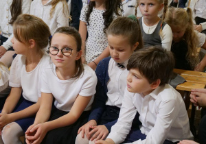 Uczniowie w sali gimnastycznej oglądają w sali gimnastycznej wystąpienie swoich kolegów z okazji Dnia Edukacji Narodowej.