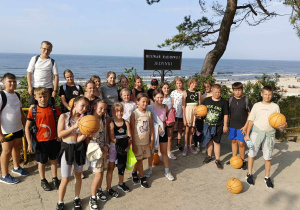 Na zdjęciu uczniowie z piłkami do kosza przy zejściu na plażę.