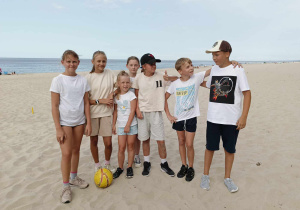 Na zdjęciu uczniowie z piłką do piłki nożnej, którzy znajdują się na plaży.