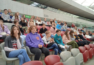 Uczniowie siedzą na trybunach Stadionu Narodowego.