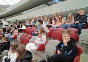 Uczniowie siedzą na trybunach Stadionu Narodowego.