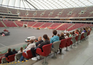 Uczniowie siedzą na trybunach Stadionu Narodowego.