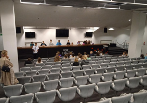 Uczniowie siedzą w sali konferencyjnej.