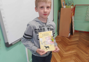 Na zdjęciu chłopiec prezentuje ulubioną książkę.