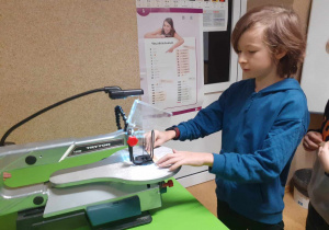 Na zdjęciu chłopiec pracuje przy wyrzynarce włosowej.