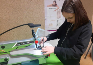 Na zdjęciu dziewczynka pracuje przy wyrzynarce włosowej.