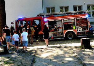 Na zdjęciu wóz straży pożarnej oraz wiele osób, które się mu przyglądają.