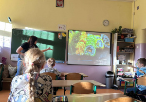 Na zdjęciu prowadząca warsztaty, która pokazuje dzieciom ciekawostki.