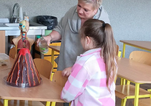 Na zdjęciu pani wicedyrektor pokazuje dziecku, jak wybucha wulkan.