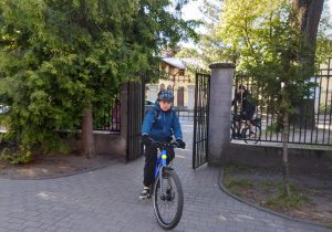 Na zdjęciu chłopiec podjeżdża do szkoły rowerem.