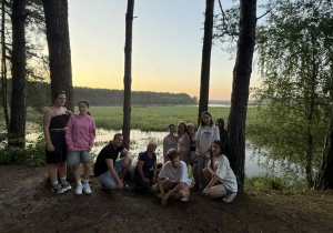 Na zdjęciu uczniowie na tle zachodu słońca nad rzeką.