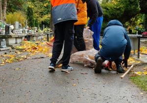 Na zdjęciu uczniowie klas 7 podczas akcji sprzątania cmentarza.