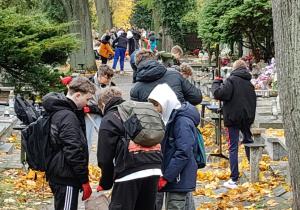 Na zdjęciu uczniowie klas 7 podczas akcji sprzątania cmentarza.