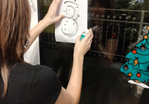 Na zdjęciu uczennica dekoruje okno.