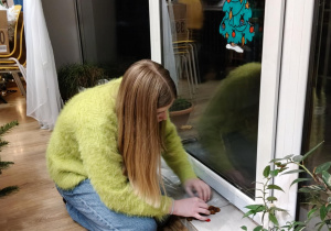 Na zdjęciu uczennica klasy 7b podczas dekorowania okna.
