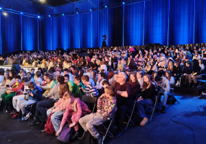 Na zdjęciu uczniowie klas 7 i 8, którzy siedzą na widowni.