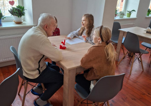 Na zdjęciu uczniowie klasy 2a prowadzą rozmowę z seniorem.
