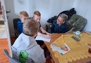 Na zdjęciu uczniowie klasy 2a prowadzą rozmowę z seniorem.