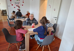 Na zdjęciu uczniowie klasy 2a prowadzą rozmowę z seniorem.