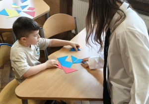 Na zdjęciu dziecko wraz z uczennicą naszej szkoły. Dziecko rozwiązuje zagadki matematyczne.