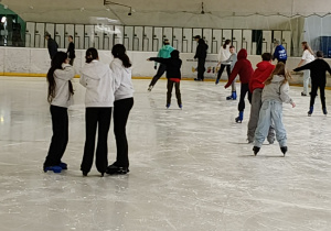 Na zdjęciu uczniowie podczas jazdy na łyżwach na lodowisku.