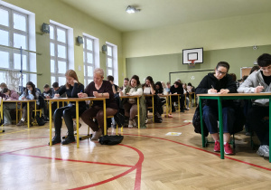 Na zdjęciu uczestnicy dyktanda piszą tekst.