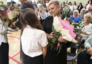 Na zdjęciu p. wicedyrektor, która dostaje od uczennicy bukiet kwiatów.
