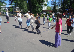 Uczestnicy Pikniku rodzinnego skaczą przez skakankę.